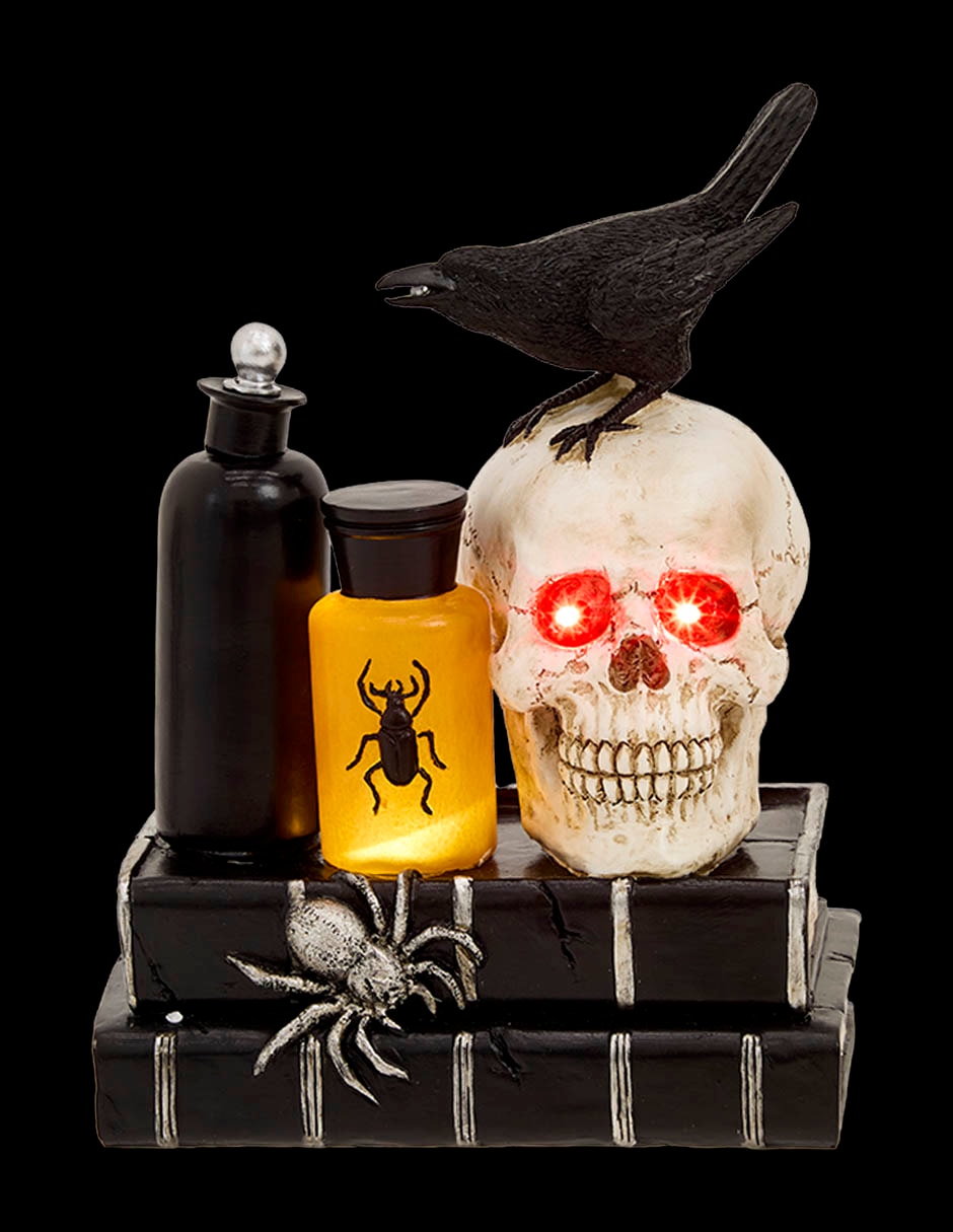 Figura decorativa de Halloween con forma de cráneo sobre libros