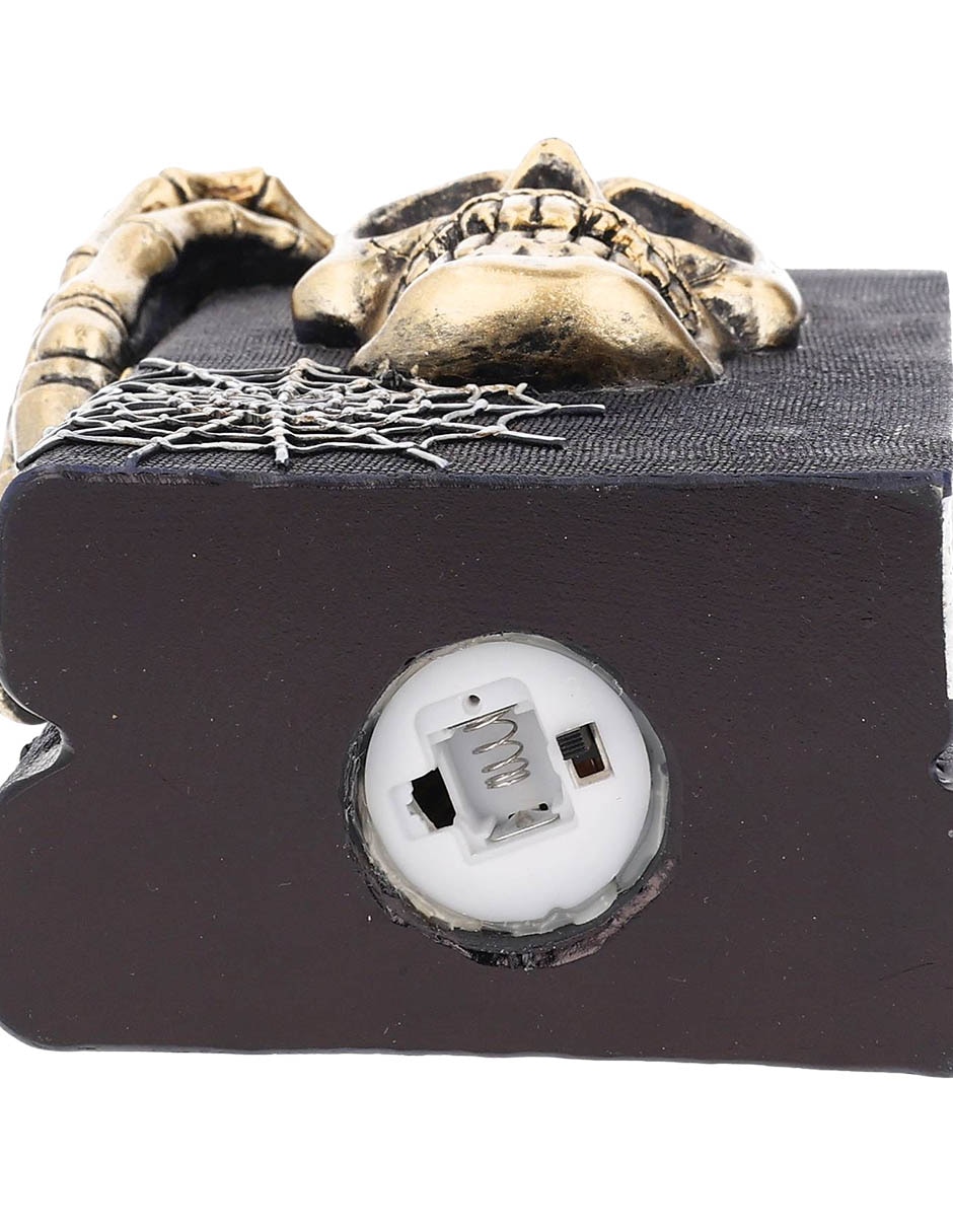 Figura decorativa de Halloween con forma de cráneo sobre libros